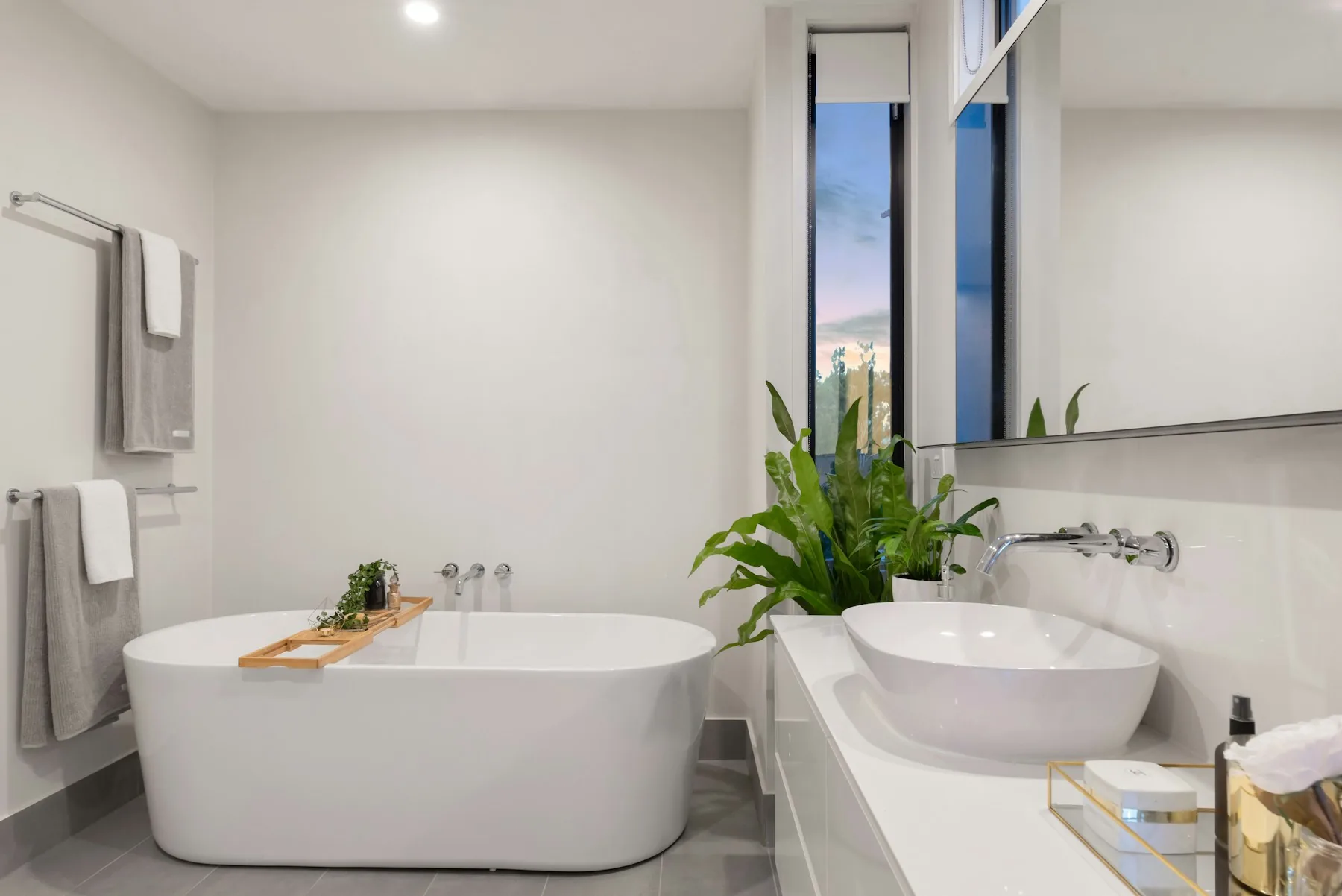Calm bathroom with a freestanding tub, neutral walls, and natural green accents